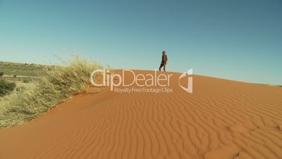 Kalahari bushman walking on blind dune horizon wide