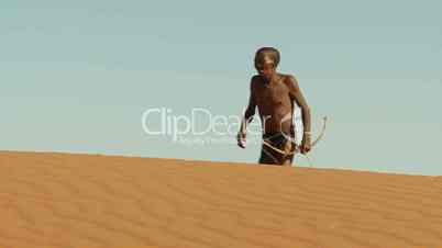 Kalahari bushman walking on blind dune horizon close