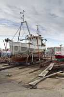 small vessel in dry dock with cloudy sky in background