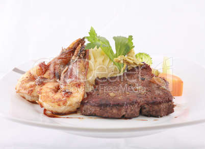 A steak and shrimp dinner over a plaid tablecloth