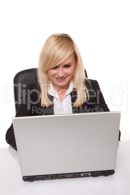 Efficient blonde businesswoman working on her laptop with her spectacles on the table alongside her