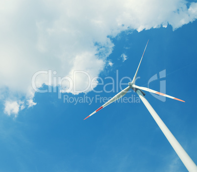 Modern wind energy turbine power station under blue sunny sky with many clouds