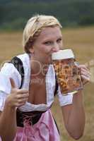 Frau im Dirndl trinkt Bier aus einem Glas