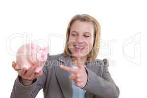 Junge Frau zeigt auf Sparschwein in ihrer Hand