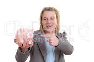 Junge Frau zeigt auf Sparschwein in ihrer Hand