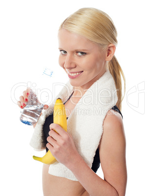 Fitness girl holding water bottle and banana