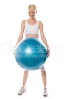 Smiling female athlete holding a big blue ball