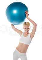 Female athlete holding blue ball, studio shot
