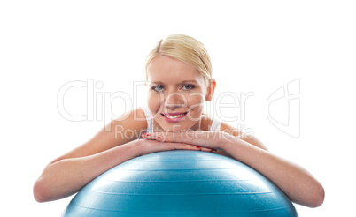 Attractive fit young woman resting chin over ball