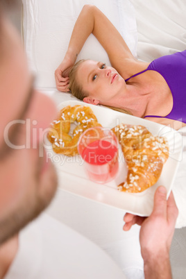 woman lying on the bed man serving breakfast