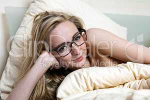 young woman is lying in bed in the morning