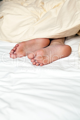 nude feets looking out of blanket in bed