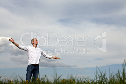 man is standing outside in spring with arms wide open and breathing