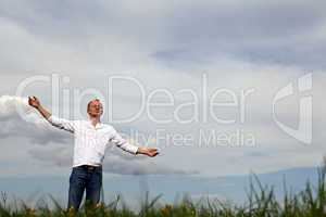 man is standing outside in spring with arms wide open and breathing