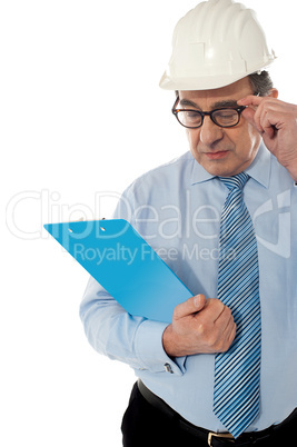 Experienced achitect in hardhat studying files. Isolated on white