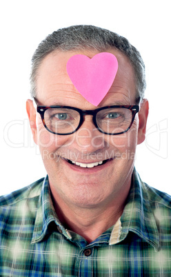 Handsome senior man with paper heart on his forehead