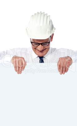 Aged builder wearning and holding a blank poster
