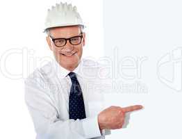 Senior man in white construction helmet holding placard