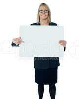 Corporate woman pointing towards blank billboard