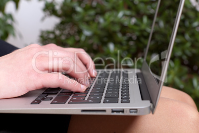 Junge Geschäftsfrau mit einem Notebook auf ihren Knien am arbeiteten