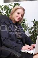 Junge elegante Geschäftsfrau sitzend mit einem weißen Netbook auf ihren Kien