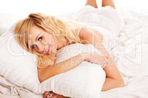 Pretty blonde hugging her pillow in the morning
