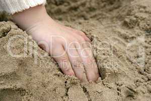 childs hand in sand