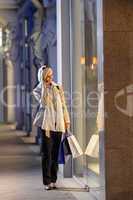Young woman window shopping evening city