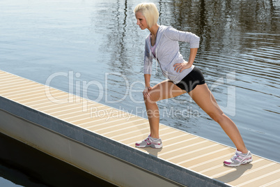 Sport woman stretch body on lake pier