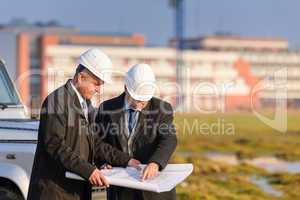 Two architects man look at construction plan