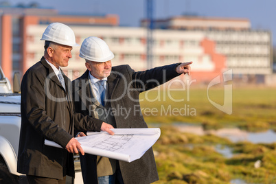 Two architects man point at construction site