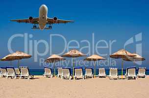 Jet flying over sunloungers on an empty beach