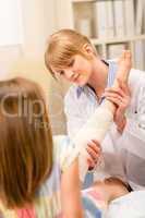 Pediatrician checking broken bandage girl leg