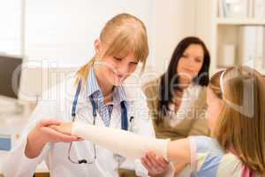 Pediatrician checking bandage girl arm