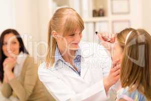 Pediatrician checking eye girl at medical office