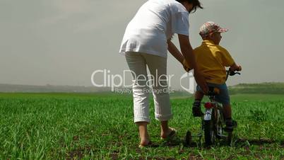 Mother teaching child to ride a bicycle