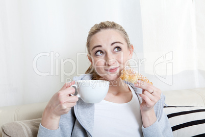 Junge Frau mit einer Tasse Kaffee und einem Croissant auf der co