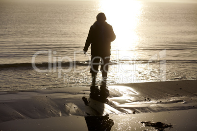 Frau mit Gummistiefeln morgens am Strand der Ostsee