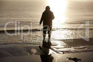 Frau mit Gummistiefeln morgens am Strand der Ostsee