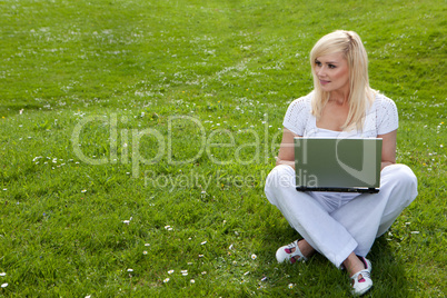 Woman with laptop on green lawn