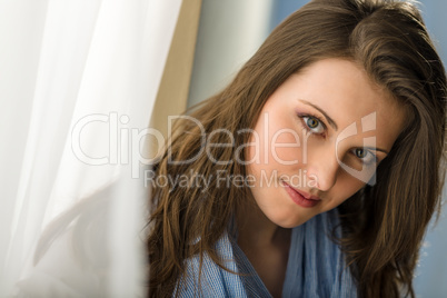 Young woman brunette look camera behind curtain