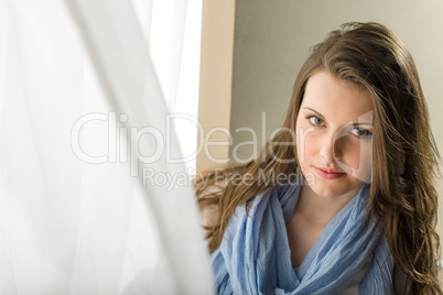 Brunette young woman behind blowing curtain