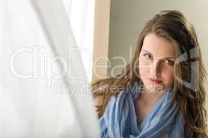 Brunette young woman behind blowing curtain