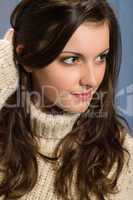 Brunette woman in beige sweater looking aside
