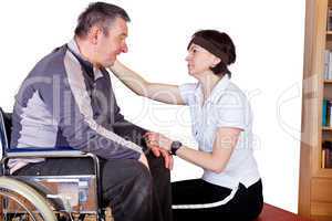 Frau spricht Mann im Rollstuhl Trost zu