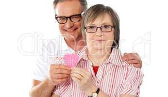 Matured smiling couple holding paper heart