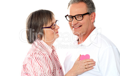 Senior couple with pink heart isolated on white