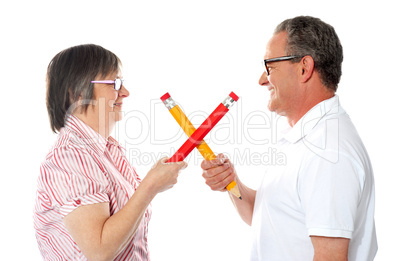 Smiling couple holding big pencils