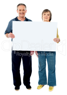 Happy senior couple holding a white placard