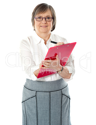 Matured professional woman writing on a red folder